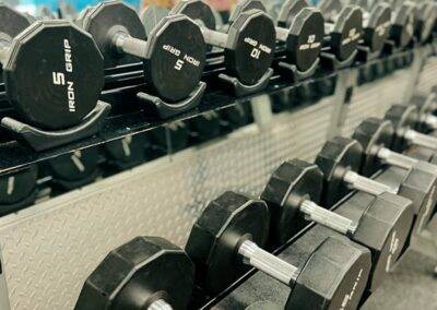 A rack of hexagonal dumbbells of various weights organized in descending order.