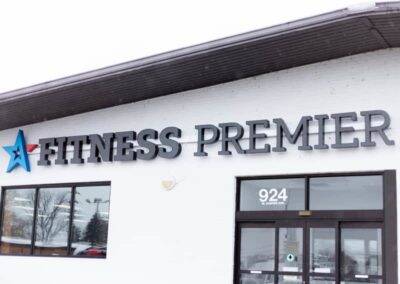 Exterior view of premier gym with brand logo and address above the entrance.