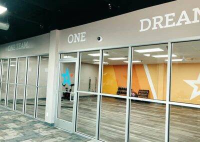 Glass-fronted office space with the words "one team. one dream." printed on the wall, visible through the windows, and colorful interior design elements.